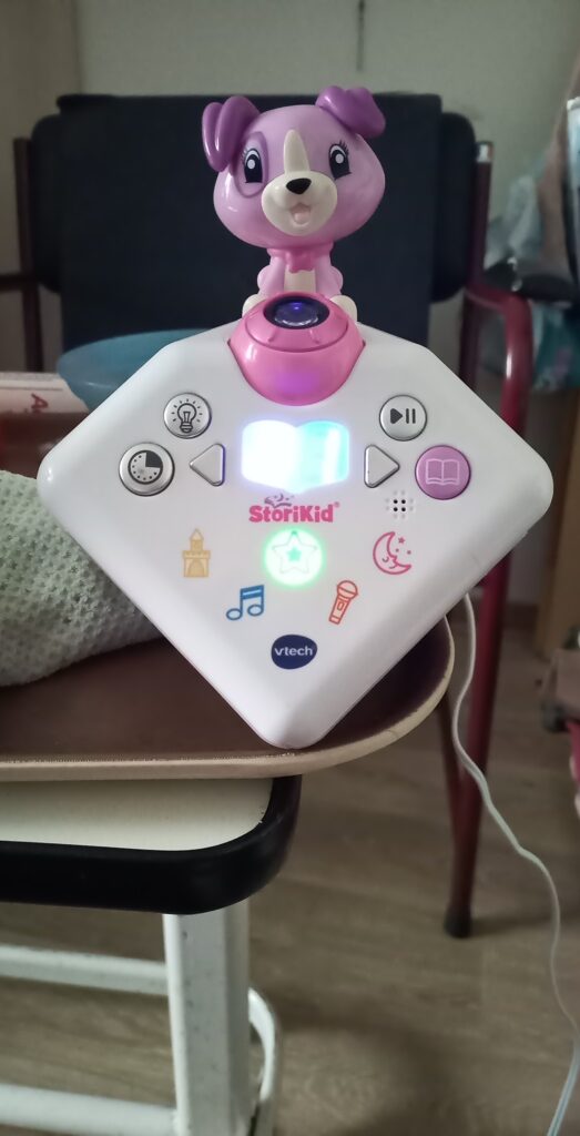 Le conteur d'histoire VTech Story'Clock avec une figurine de chien, posé sur une table, vue de face.
