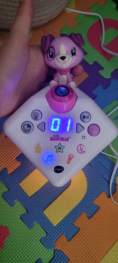Gros plan sur le dessus du conteur d'histoire VTech Story'Clock, avec un écran affichant "01" et des icônes lumineuses.