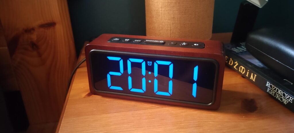 Réveil posé sur une table de chevet, affichant l'heure 20:01