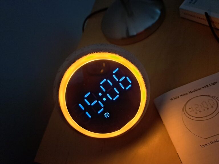 Le radio-réveil est posé sur une table de nuit, avec une notice à côté. La lumière d'ambiance est allumée et l'heure est 15:0...