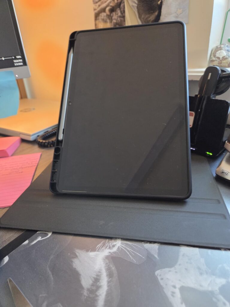 Tablette noire sur un support dans un intérieur, vue de face légèrement décentrée.