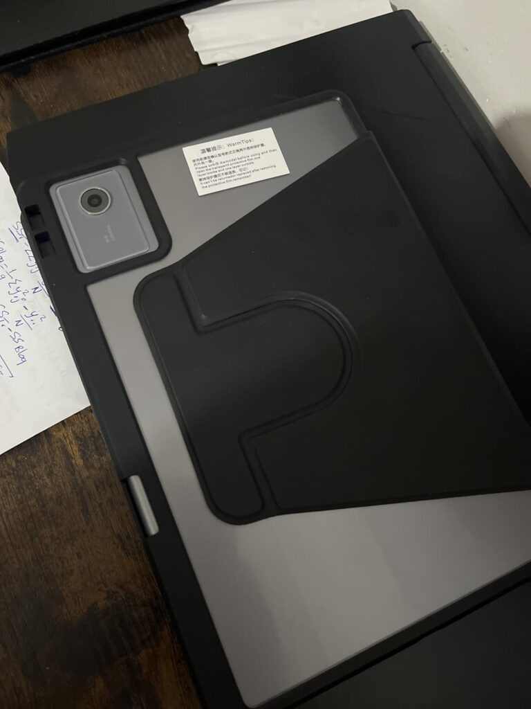 Arrière d'une tablette noire avec un support pliable et une étiquette. Vue en plongée sur un bureau.