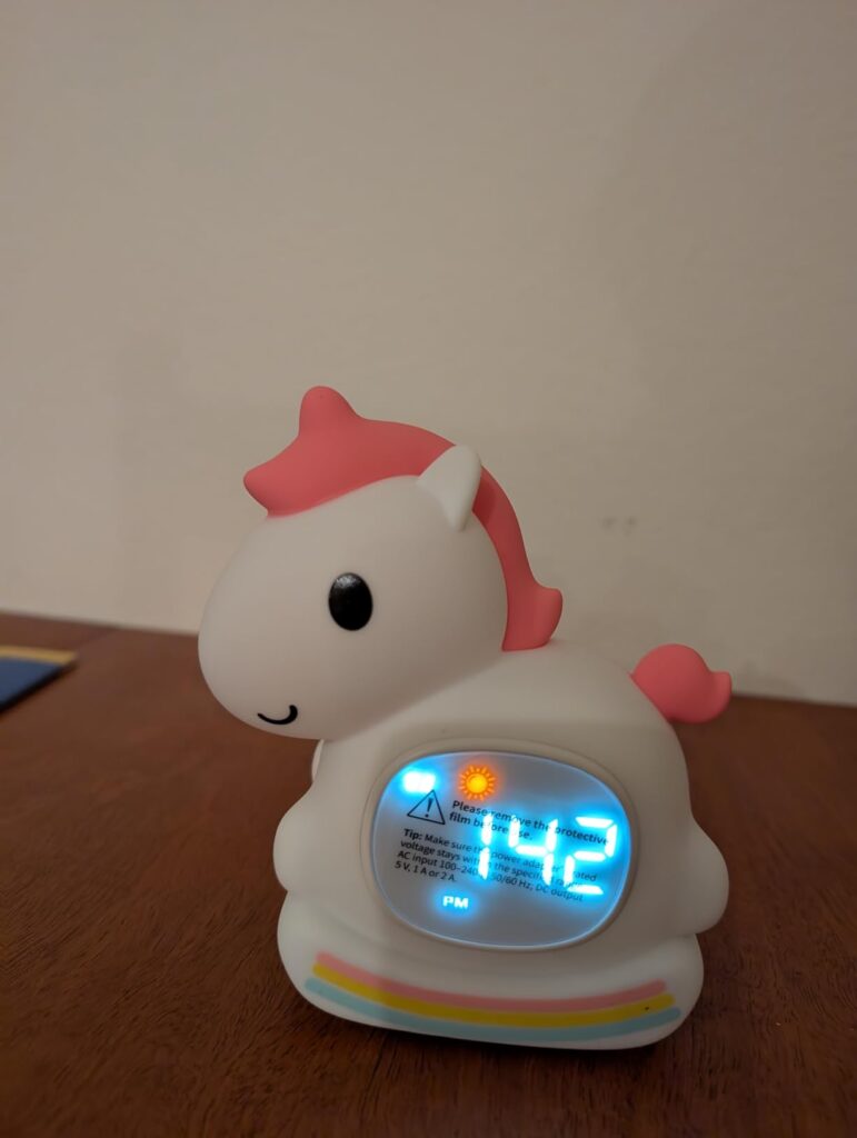La licorne posée sur une table de chevet, l'heure est affichée.