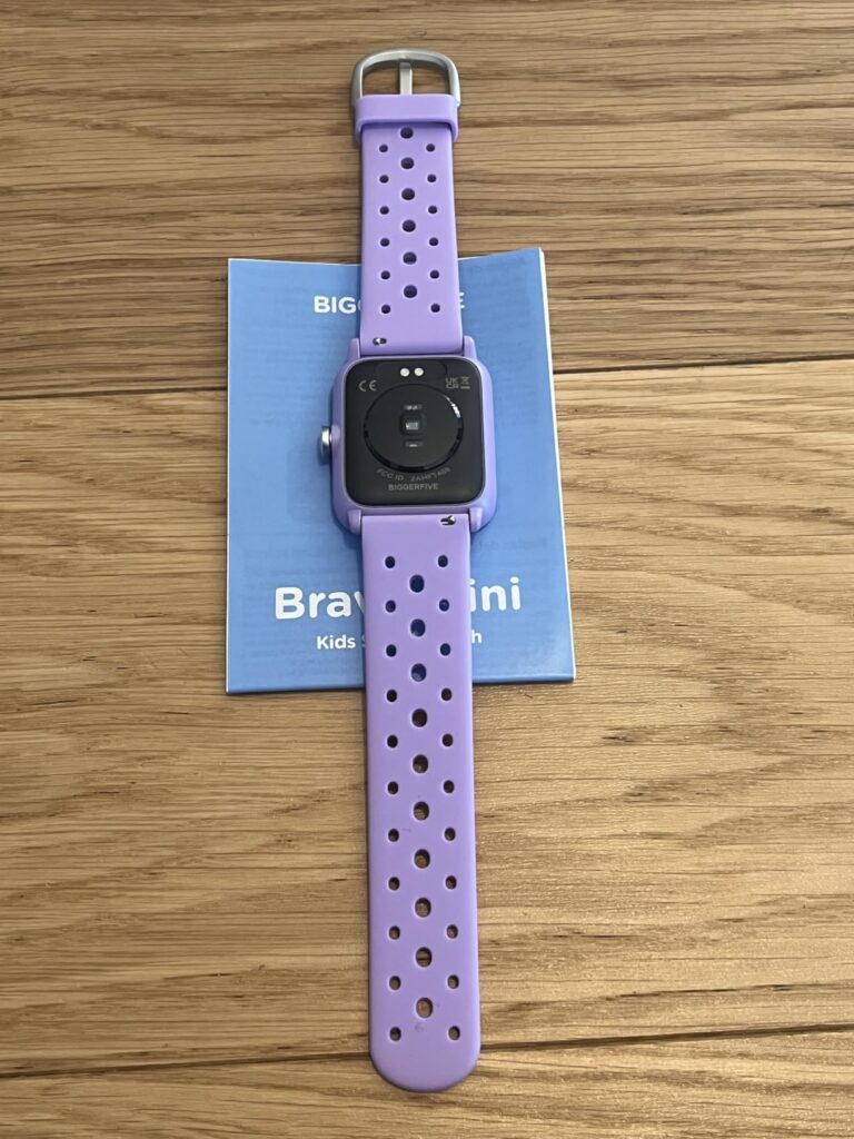 Vue arrière de la montre connectée violette posée sur le livret.