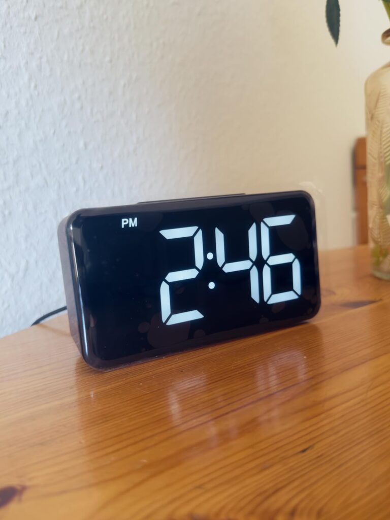 L'horloge posée sur un meuble en bois, affichant l'heure.