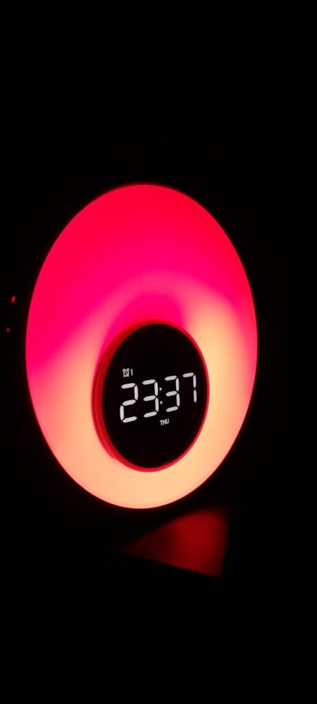 Le réveil lumière en situation dans un intérieur sombre avec un éclairage rouge/rose.