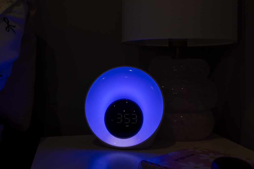 Le réveil lumière sur une table de chevet, avec une lumière bleue et l'heure affichée.