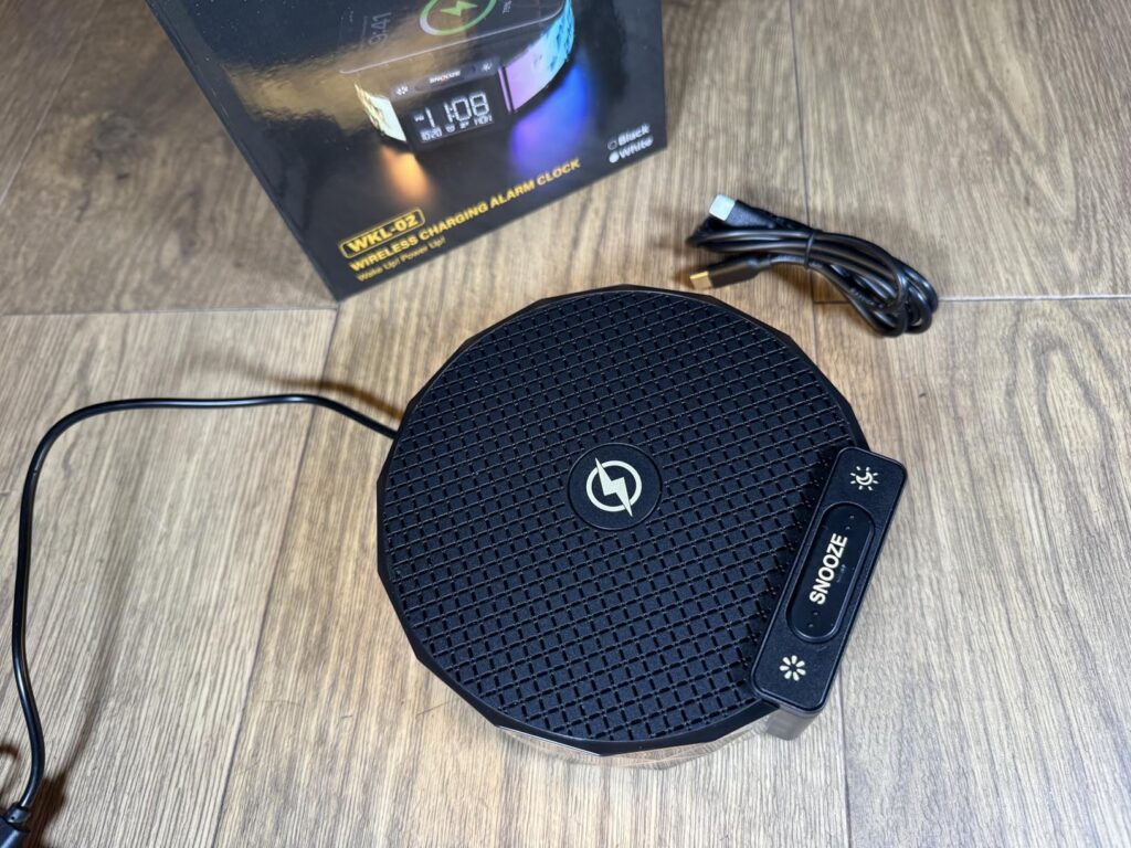 Le radio-réveil et son emballage vus de dessus, avec le câble de charge et le boîtier des réglages séparé.