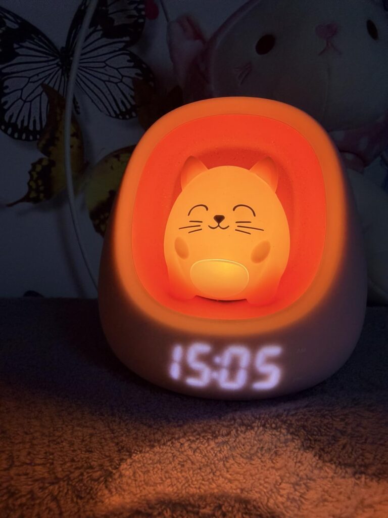L'appareil est allumé dans le noir. Il éclaire avec une lumière orange et affiche l'heure. Un arrière-plan flou de chambre d'...