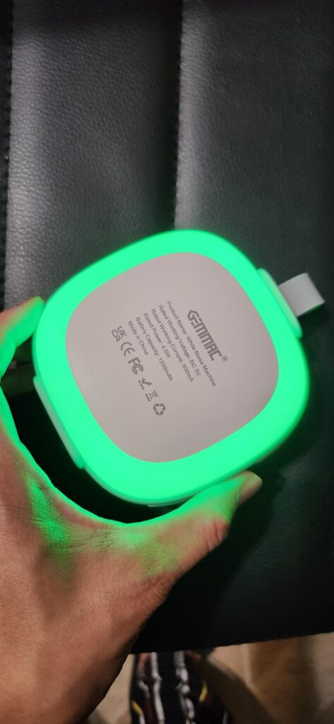 Vue du dessous du produit tenu dans une main, avec la lumière verte visible et des informations imprimées.