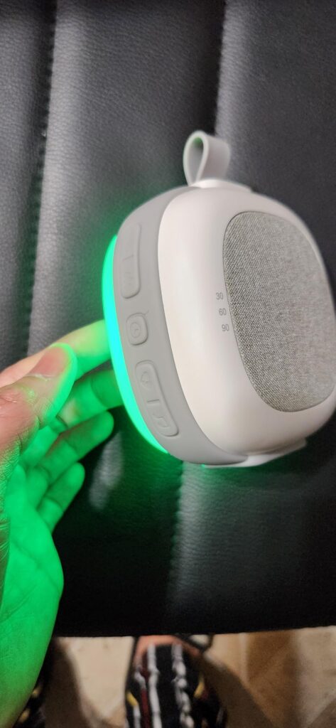 Vue latérale du produit tenu dans une main, avec des boutons et une lumière verte visible.