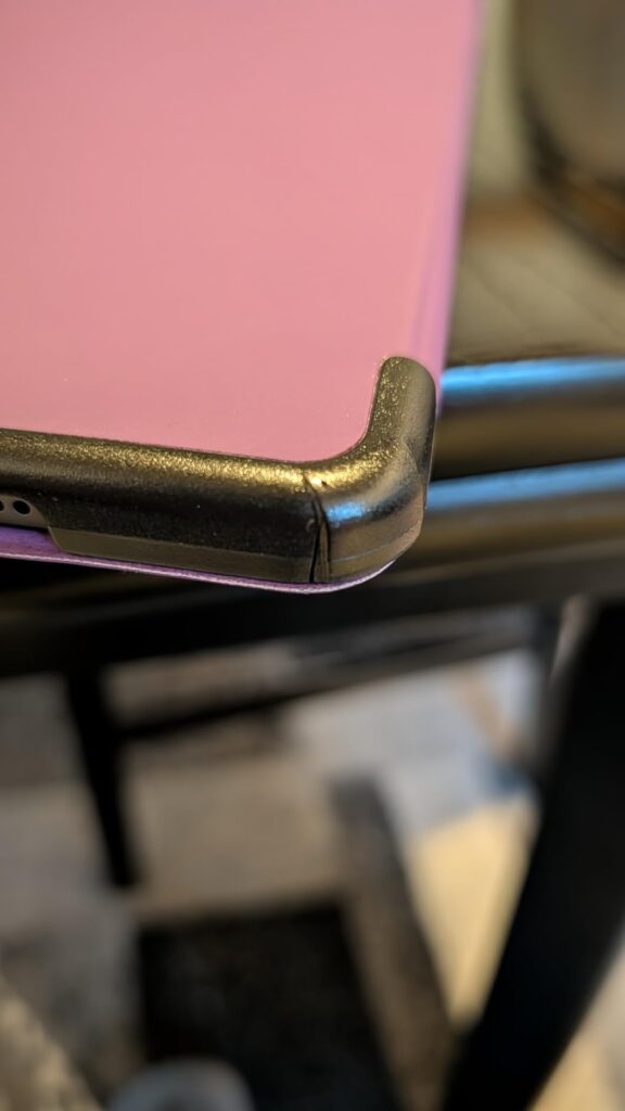 Gros plan sur l'angle d'une tablette protégée par une coque rose. L'angle de la coque est cassé.
