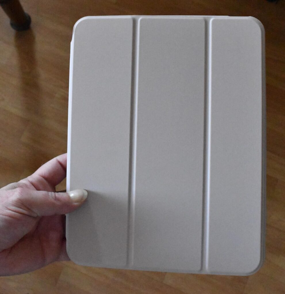 La coque est tenue par une main, montrant le rabat avant avec les trois plis qui permettent de la replier pour former un supp...