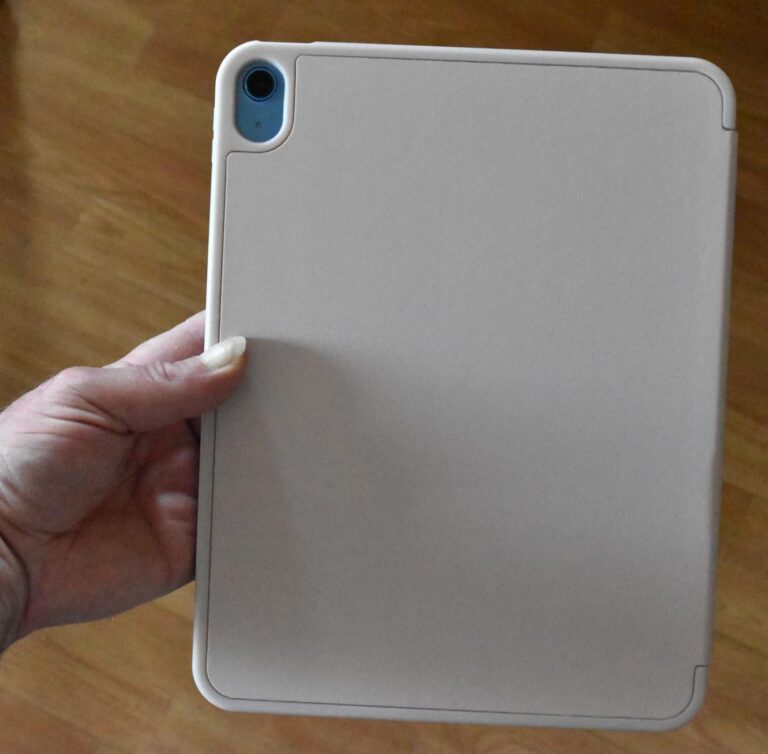 Une tablette est insérée dans la coque, tenue par une main. L'objectif de l'appareil photo de la tablette est visible à trave...