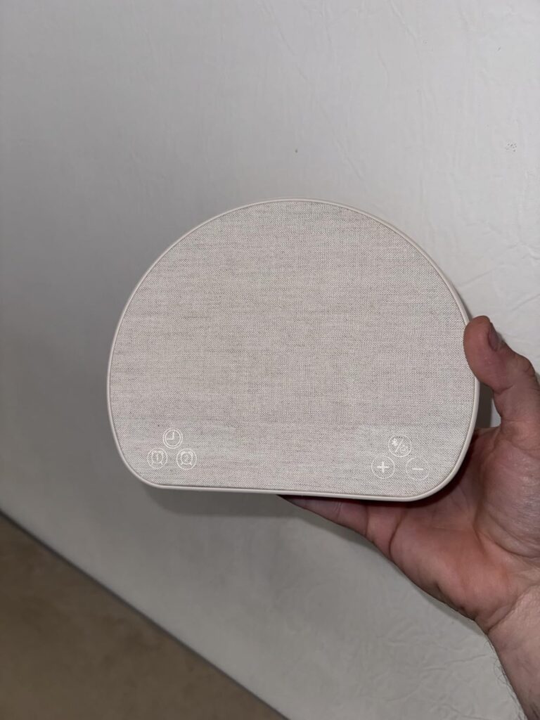 Une personne tient le réveil-lumière dans sa main. On peut voir la texture du tissu et les boutons de contrôle.