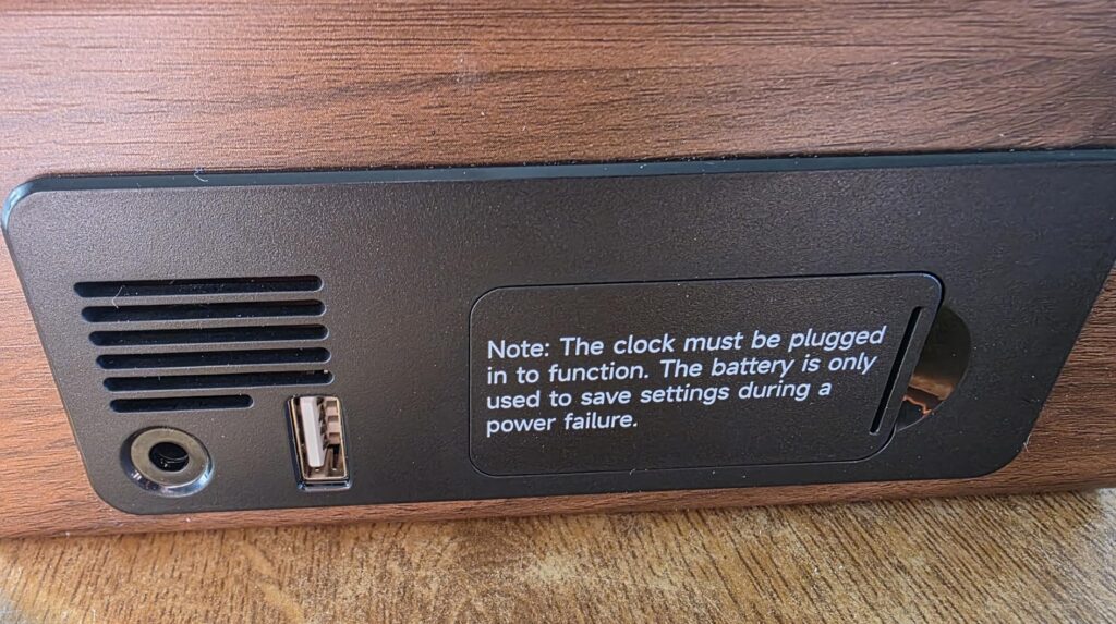 L'arrière du réveil, avec les prises USB et jack, ainsi qu'une grille de ventilation. On voit aussi un texte d'avertissement...