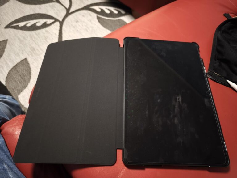 Tablette avec sa coque de protection ouverte sur un canapé rouge