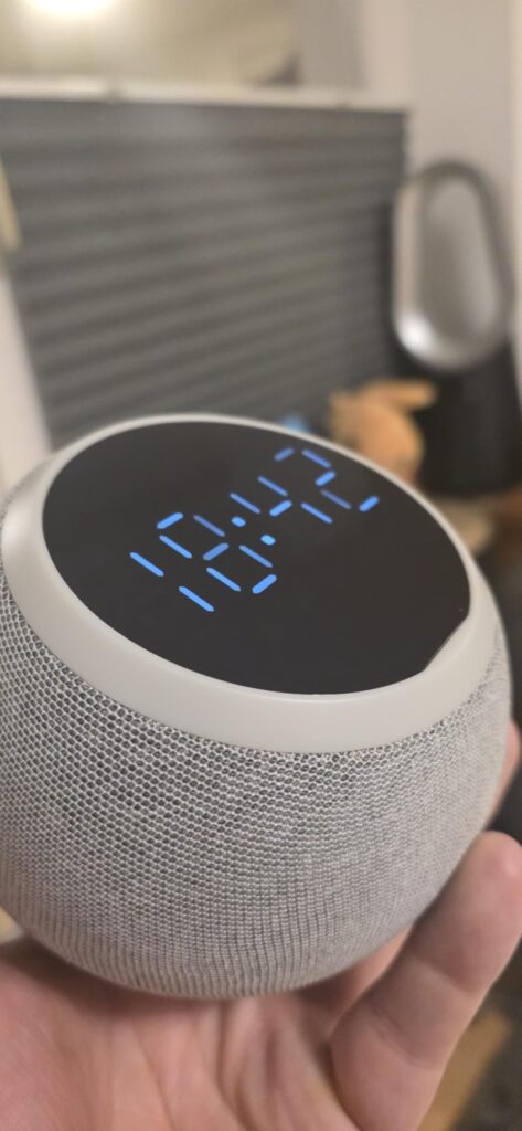 L'enceinte est tenue dans une main, l'heure 10:42 est affichée.