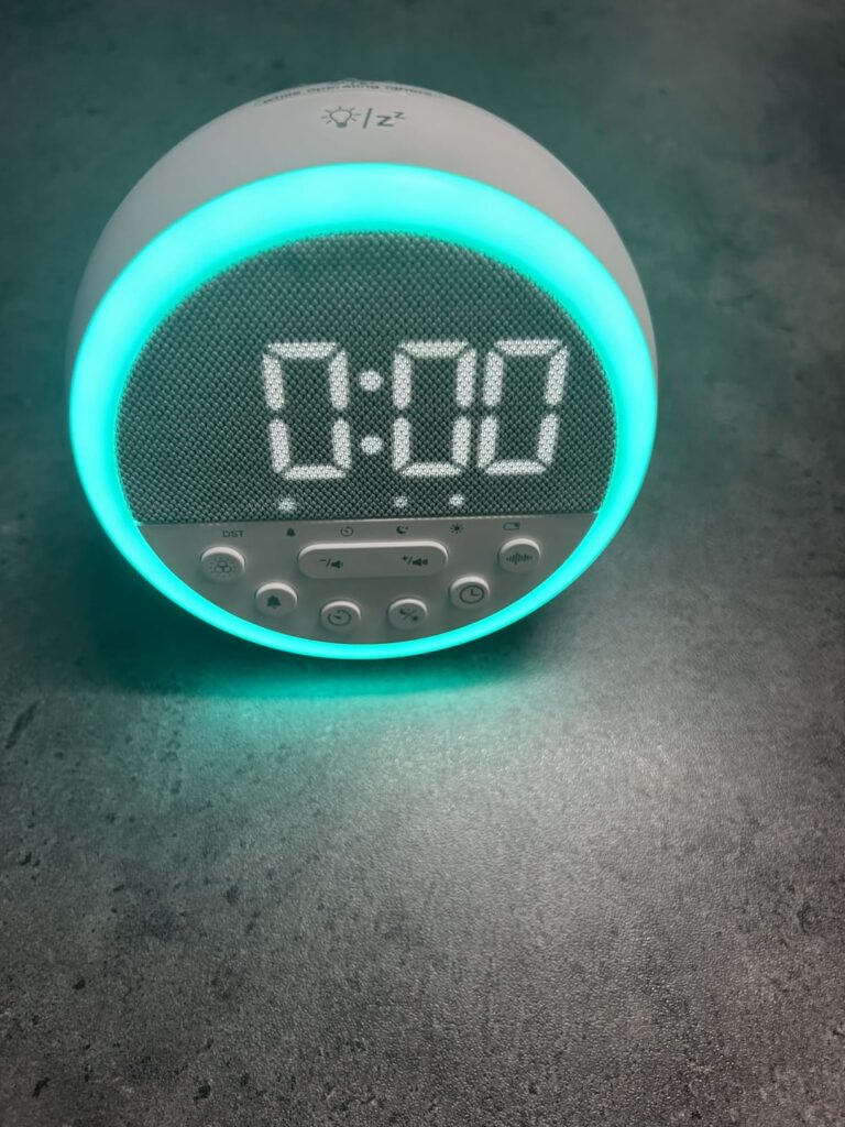 L'horloge LED multifonctionnelle GEMMAC allumée, affichant l'heure 0:00 et une lumière ambiante bleue. L'angle de prise de vu...
