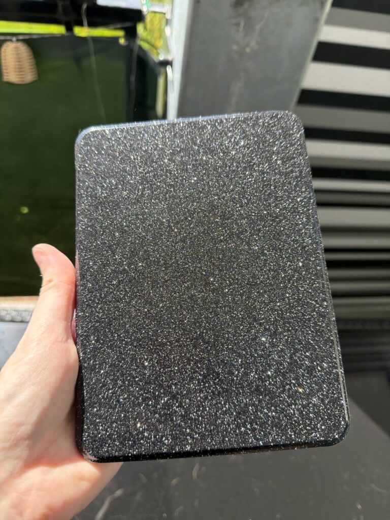 Gros plan sur l'étui de protection avec un motif texturé scintillant, tenu dans une main.