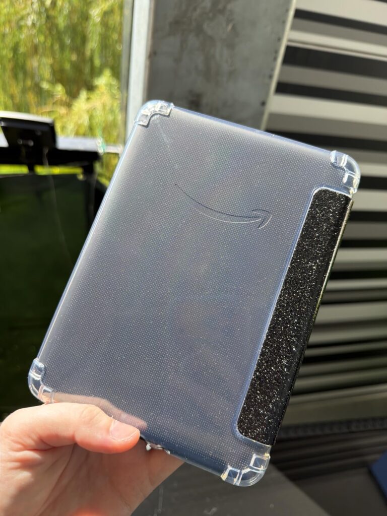 L'arrière de l'étui transparent pour liseuse, montrant le logo Amazon, tenu dans une main.