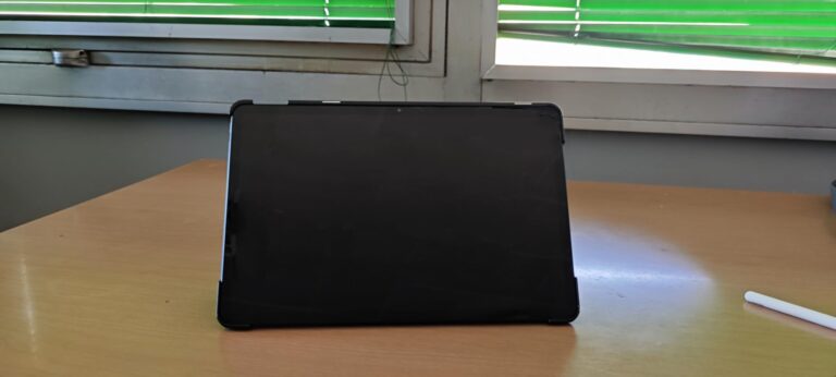 Vue de face de la tablette dans son étui posée sur une table, face à une fenêtre.