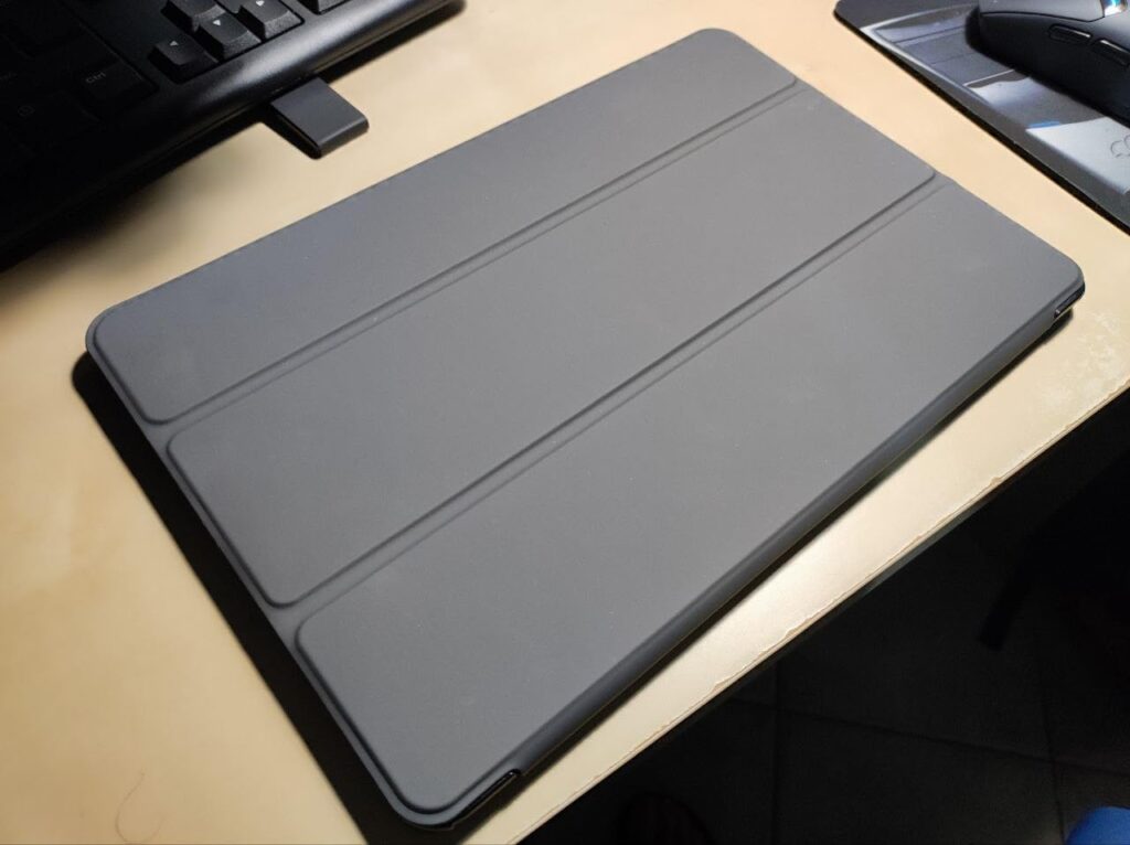 Vue en plongée de l'étui de la tablette fermé, posé sur un bureau. On aperçoit un clavier et une souris à côté.