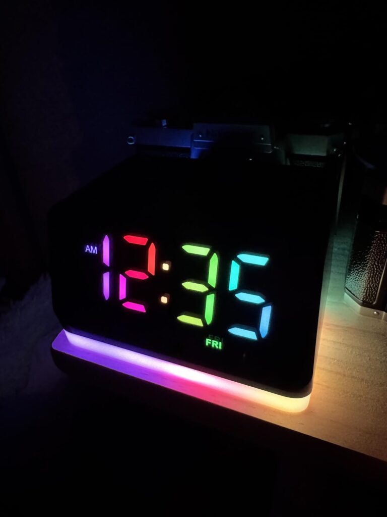 Le radio-réveil dans la pénombre, affichant l'heure en couleurs et l'anneau lumineux de base en différentes couleurs.