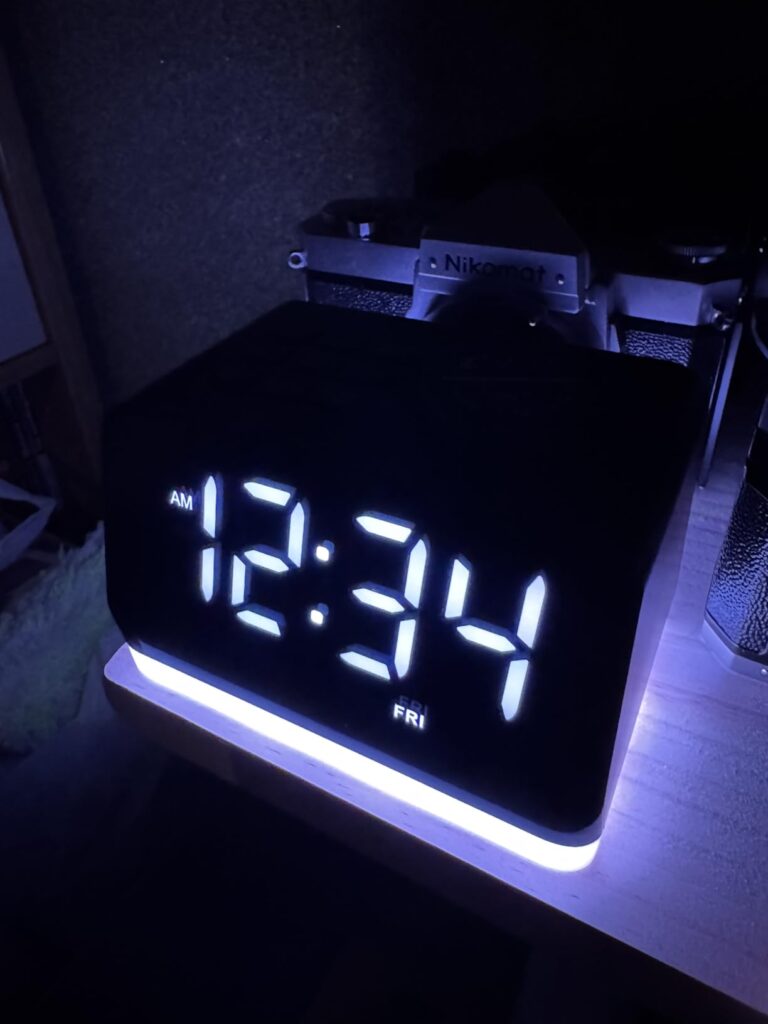 Le radio-réveil dans la pénombre, affichant l'heure en blanc et l'anneau lumineux de base en violet.
