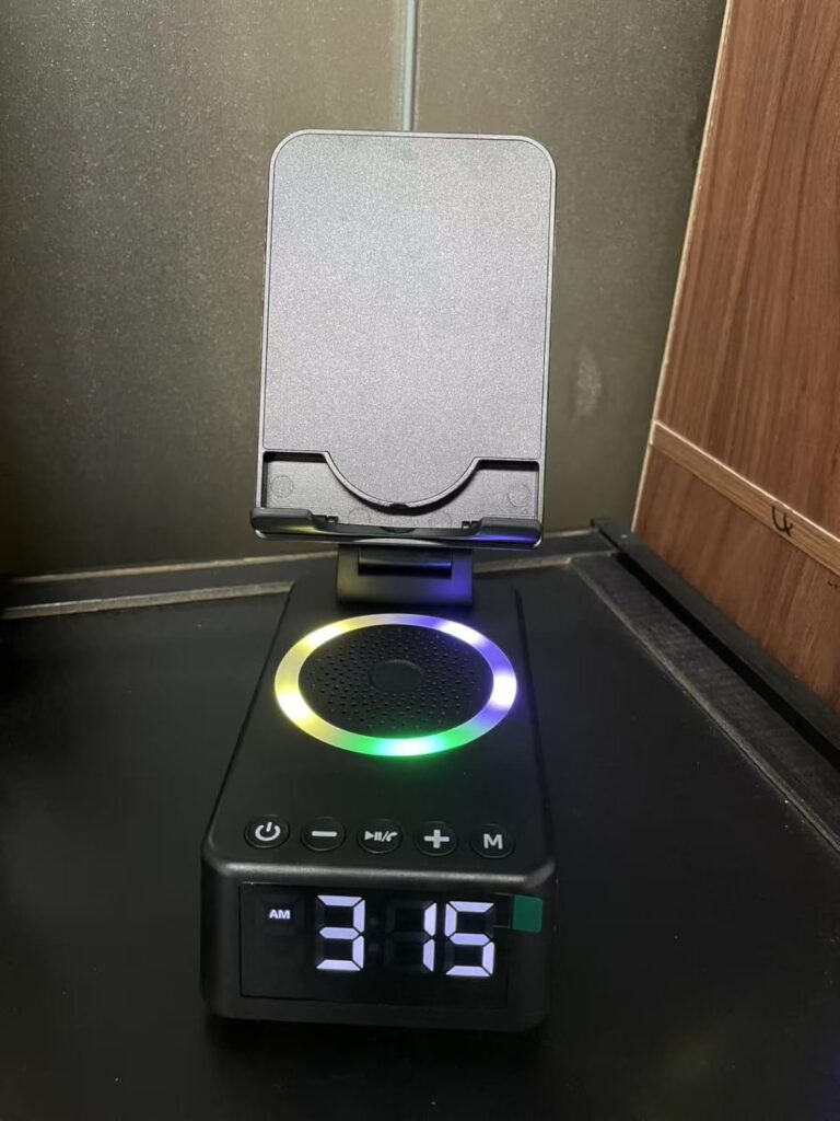 Le produit de face, avec le support de téléphone déplié mais sans téléphone. L'éclairage RGB est allumé et l'heure est affich...