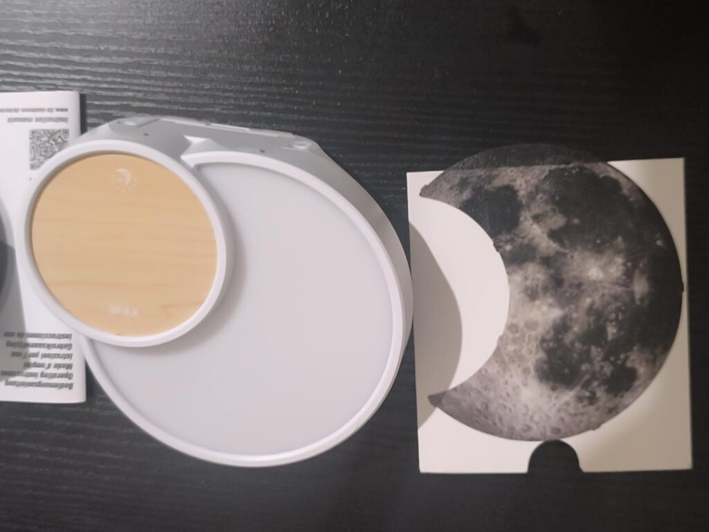 Vue de dessus de l'appareil et de l'image de lune. L'appareil est posé sur une table noire. Il est partiellement déballé.