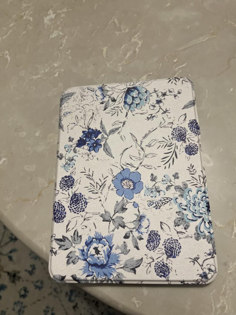 L'étui fermé avec un motif floral bleu et blanc, posé sur une table.
