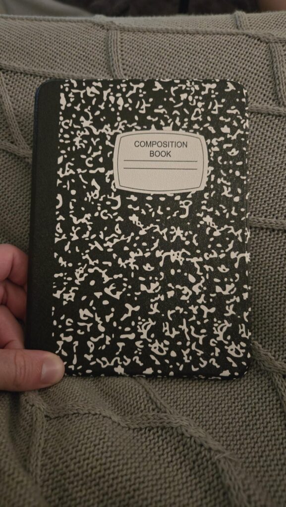 Liseuse fermée, couverture imitation cahier d'école. Tenue à la main.