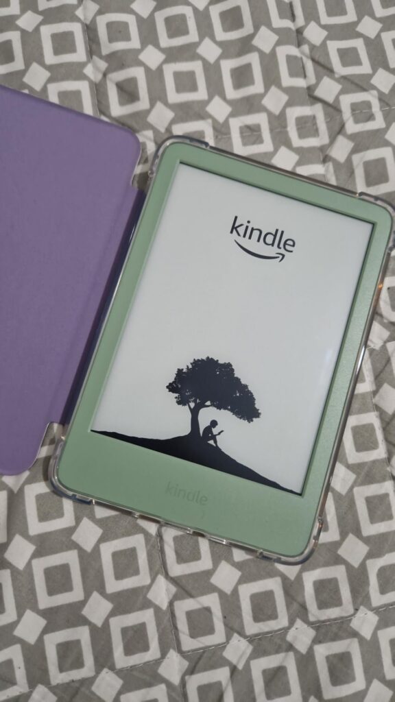 La liseuse Kindle Paperwhite avec une coque de protection de couleur vert clair et un étui violet ouvert, posée sur un tissu...