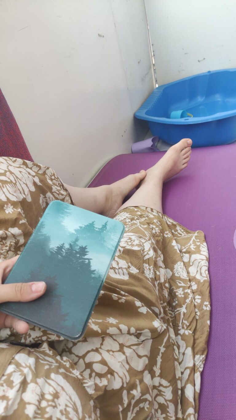 Une personne lit un livre sur une liseuse Kindle Paperwhite, recouverte d'une coque avec un motif de forêt, dans un environne...