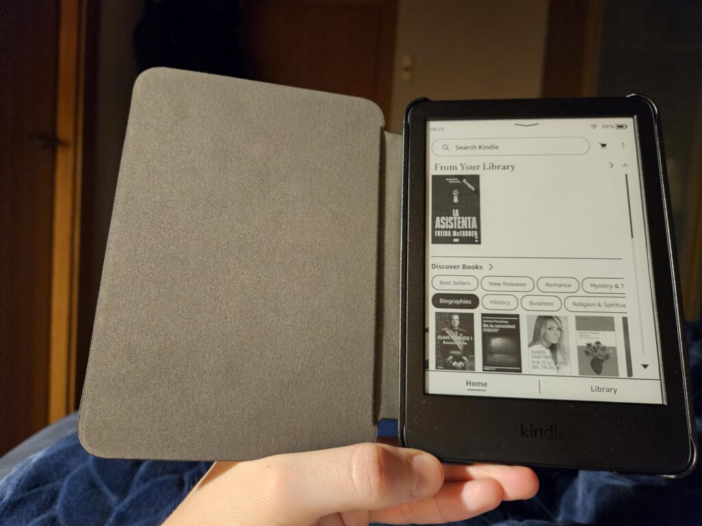 Vue de dessus d'une liseuse Kindle Paperwhite, recouverte d'un étui. L'étui est ouvert et posé sur un tissu. La liseuse est a...