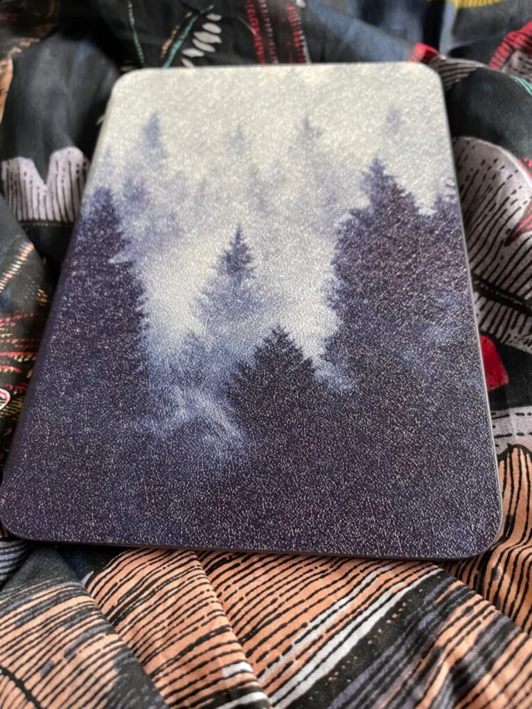 Vue de dessus d'une liseuse Kindle Paperwhite, recouverte d'un étui. L'étui est ouvert et posé sur un tissu.