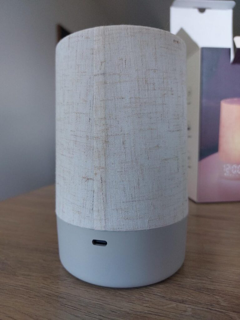 Gros plan sur le réveil posé sur une table, montrant la texture du tissu et l'unique bouton en façade.