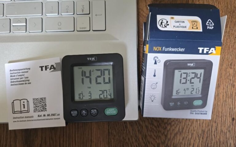 Le radio-réveil sur un bureau avec un ordinateur portable et la boîte d'emballage, affichant 14h20, 10 mars et 20,4 degrés.