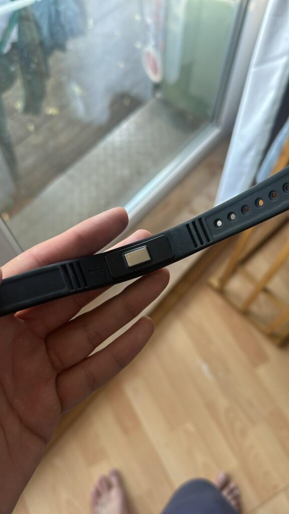 Gros plan sur le bracelet tenu dans une main, montrant la partie qui se connecte au chargeur.