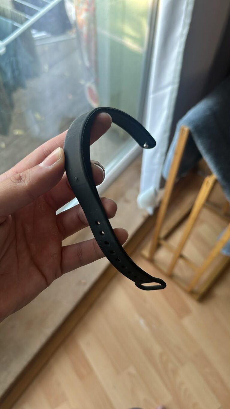 Le bracelet tenu dans une main, avec une fenêtre en arrière-plan.