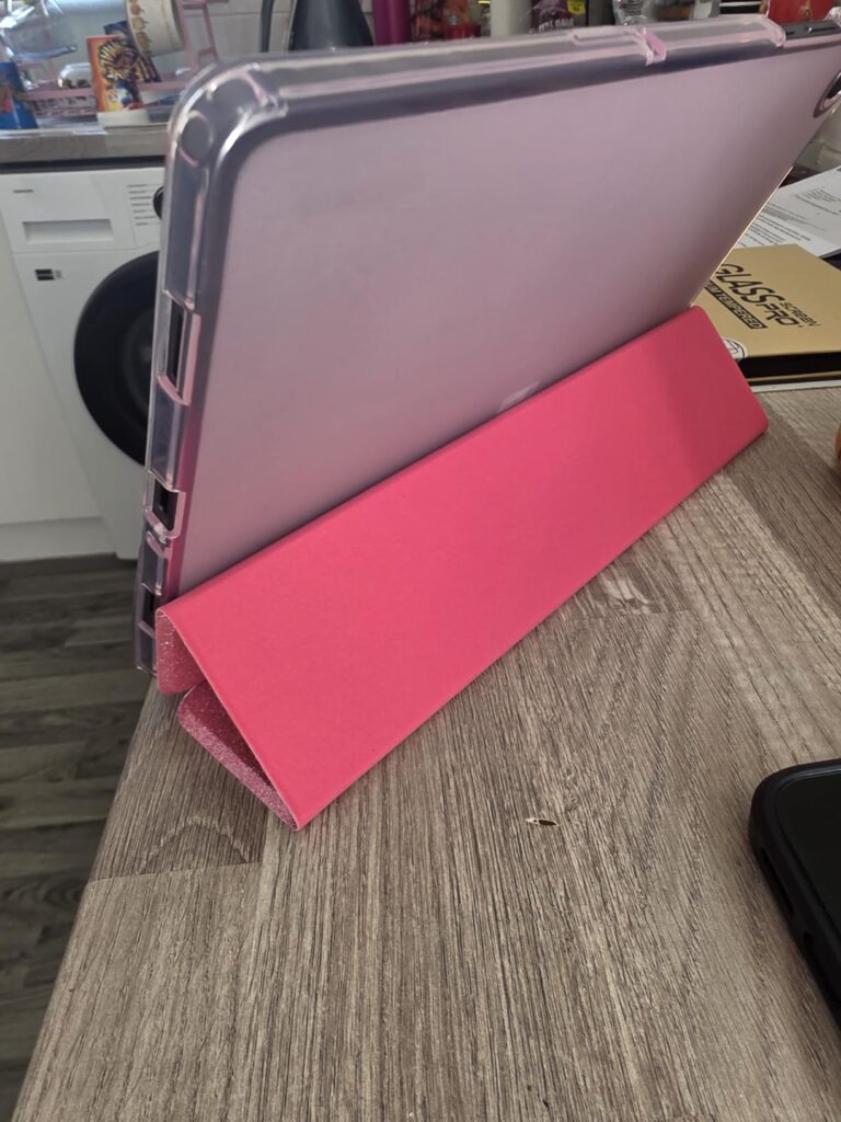 Tablette tenue par son étui pliable, posée sur une table en bois.