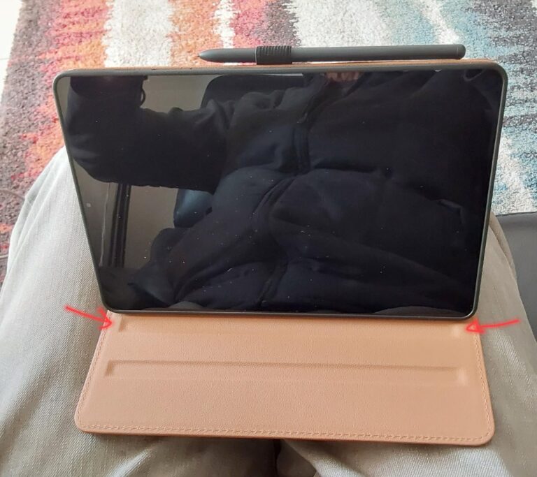 La tablette est posée sur les genoux d'une personne, maintenue par sa coque ouverte. La coque fait office de support.