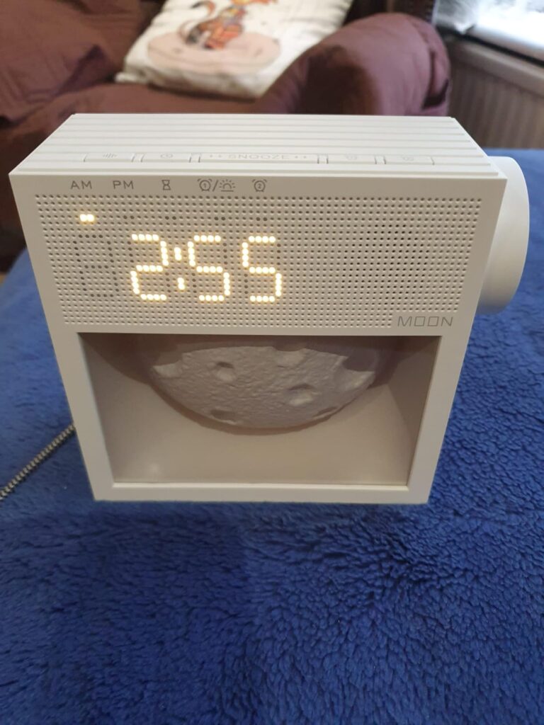 Le radio-rveil est pos sur une table, dans une pice. Son cran affiche l'heure.