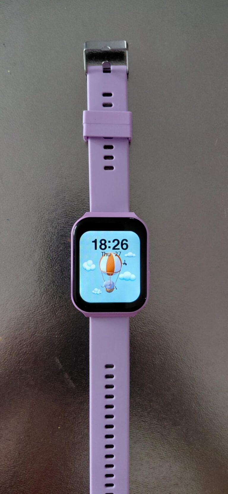 Vue d'ensemble de la montre connectée, écran affichant l'heure et un fond d'écran coloré avec un ballon dirigeable.